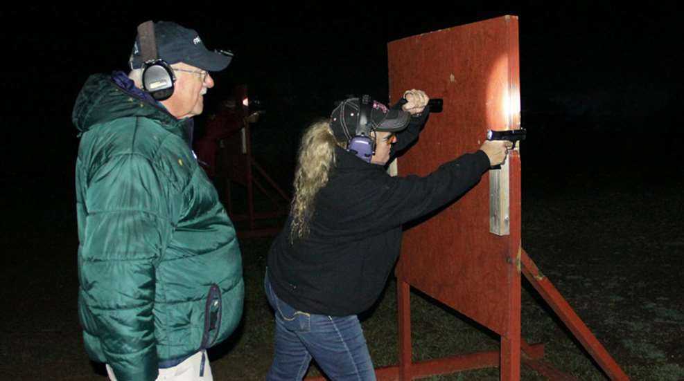 woman shoots from behind barricade at dusk
