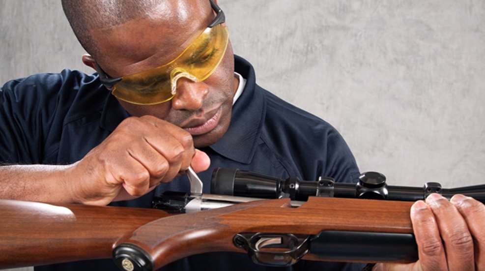 young man checking breech of rifle