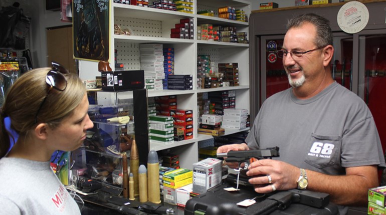 gun store clerk demonstrates unloaded firearm for possible buyer
