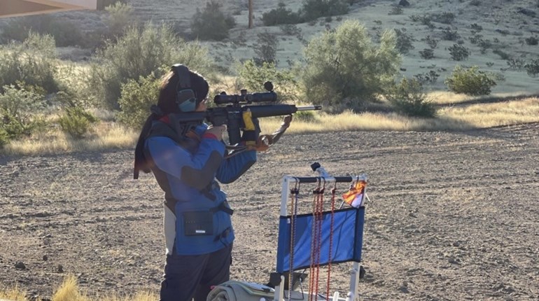 Lucy Kores in competitive shooting gear and safety equipment shooting in the desert