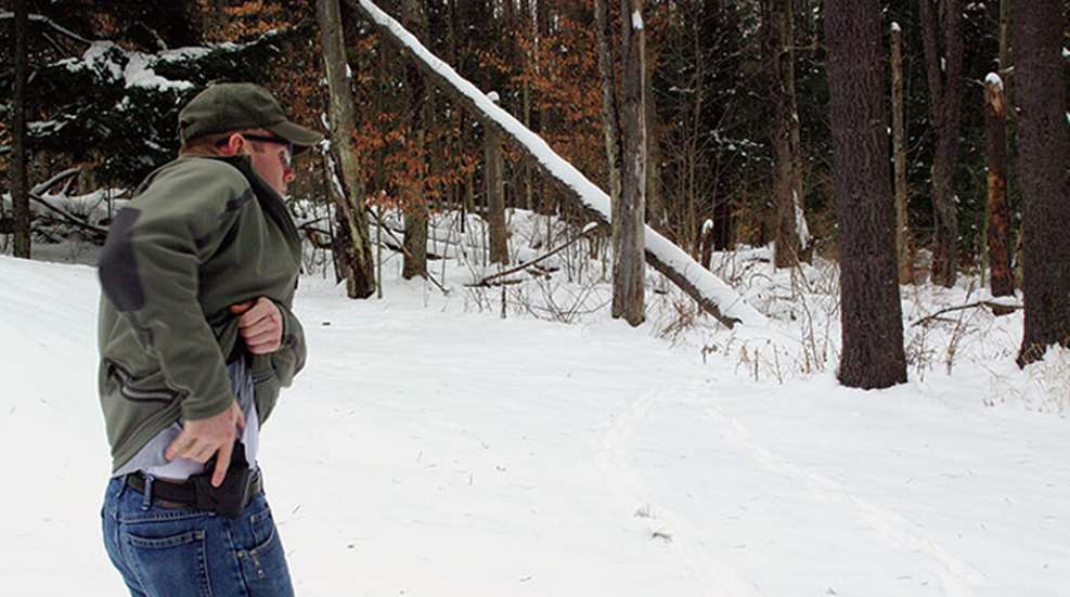 man draws from concealment under winter jacket