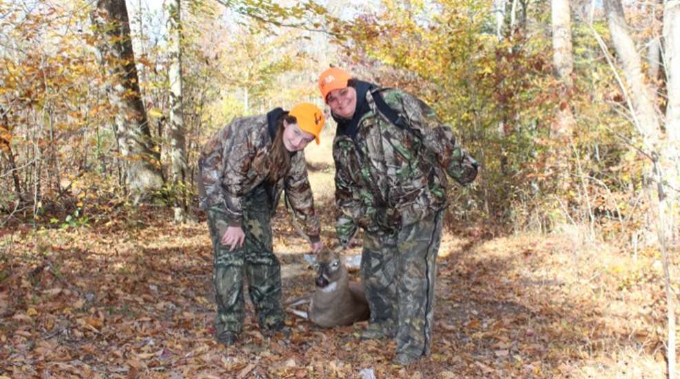 two young huntresses dragging a small buck