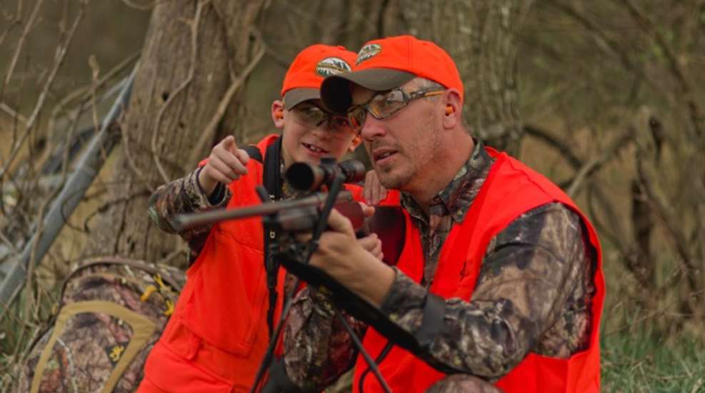 adult coaches child with rifle