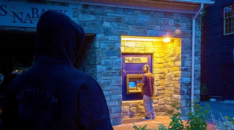 crook looms over man at ATM