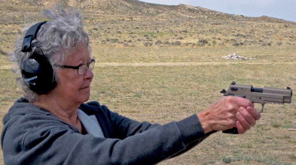 elderly woman takes aim with pistol